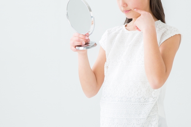 口もとを鏡でみる女性 口もとを鏡でみる女性